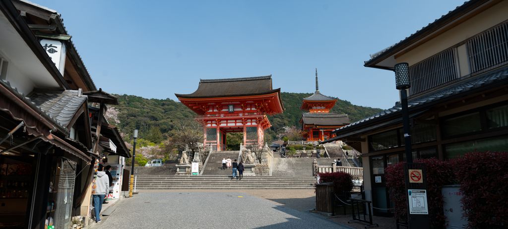 参道の先に立つ朱塗りの門と三重塔